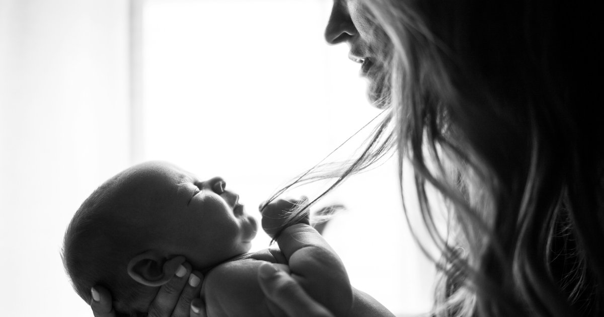 A black-and-white photo of a mother gently kissing her newborn.